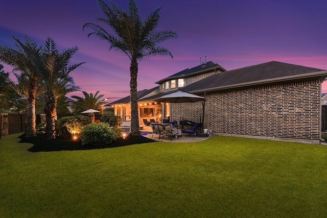 5702 Mustang Ridge Ln, Fulshear, TX 77441 - back of house at dusk featuring a patio and brick siding