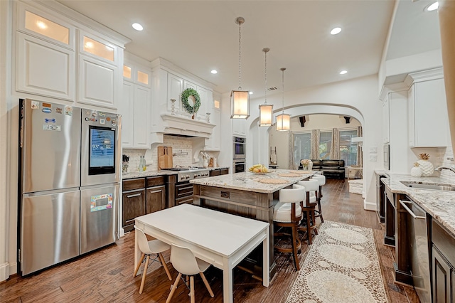 105 Checkerbloom Ct, Montgomery, TX 77316 - kitchen with appliances with stainless steel finishes, arched walkways, a kitchen island, a sink, and glass insert cabinets