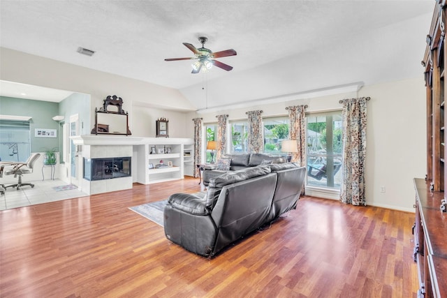 17503 Whispering Star Ct, Houston, TX 77095 - living area with a ceiling fan, wood finished floors, a tile fireplace, vaulted ceiling, and a textured ceiling