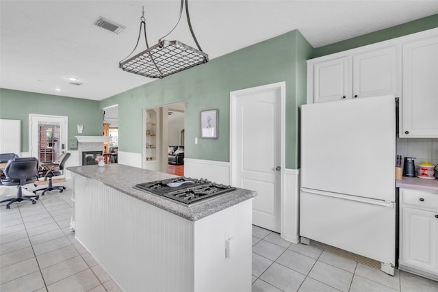 17503 Whispering Star Ct, Houston, TX 77095 - kitchen featuring freestanding refrigerator, stainless steel gas cooktop, light tile patterned floors, a center island, and white cabinetry