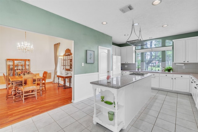 17503 Whispering Star Ct, Houston, TX 77095 - kitchen featuring light tile patterned flooring, recessed lighting, a center island, white cabinetry, and wainscoting