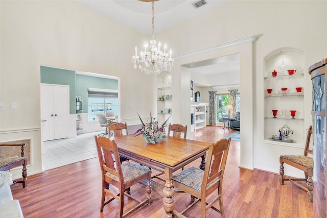 17503 Whispering Star Ct, Houston, TX 77095 - dining room featuring built in shelves, wood finished floors, a chandelier, and a high ceiling