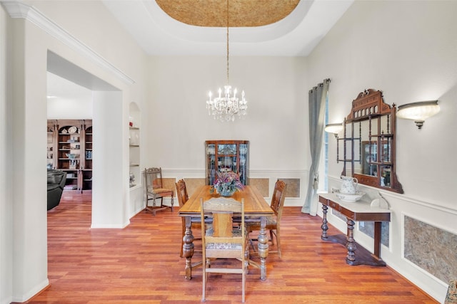 17503 Whispering Star Ct, Houston, TX 77095 - dining room with arched walkways, a chandelier, a towering ceiling, built in shelves, and wood finished floors