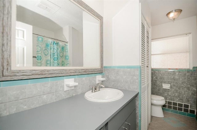 4410 Spellman Rd, Houston, TX 77035 - bathroom with toilet, tile walls, vanity, tile patterned flooring, and a wainscoted wall