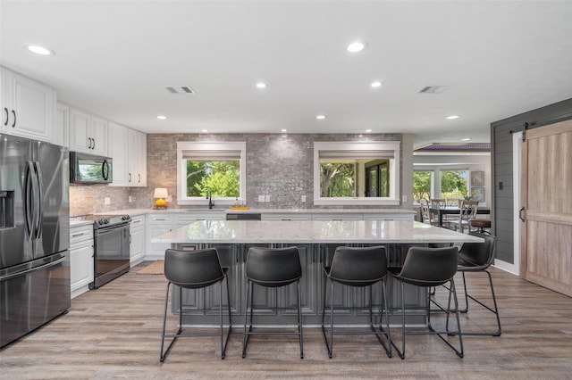 719 Fairfield St, Shoreacres, TX 77571 - kitchen featuring black appliances, healthy amount of natural light, white cabinets, tasteful backsplash, and recessed lighting