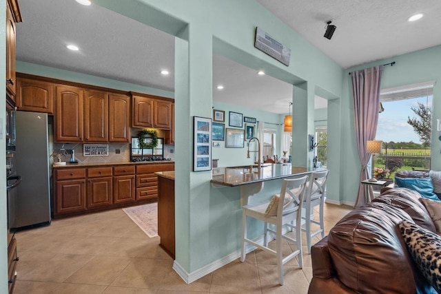 4510 Bonita Way, League City, TX 77573 - kitchen with freestanding refrigerator, brown cabinetry, a sink, a breakfast bar, and open floor plan