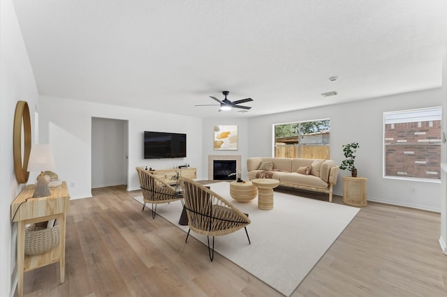 2411 Irish Spring Dr, Houston, TX 77067 - living area with light wood-style floors, a tile fireplace, a ceiling fan, and baseboards