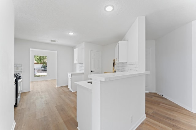 2411 Irish Spring Dr, Houston, TX 77067 - kitchen featuring stainless steel range with gas cooktop, light wood-style flooring, white cabinets, baseboards, and light countertops