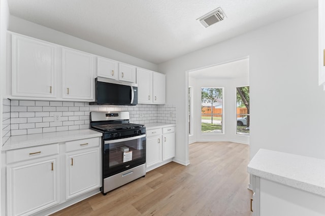 2411 Irish Spring Dr, Houston, TX 77067 - kitchen featuring appliances with stainless steel finishes, backsplash, white cabinetry, and light wood-style floors