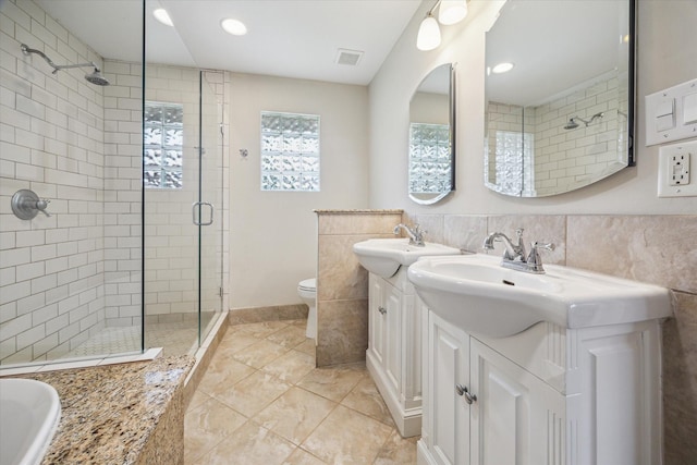 2910 Ann Arbor Dr, Houston, TX 77063 - bathroom featuring a stall shower, two vanities, toilet, recessed lighting, and tile walls