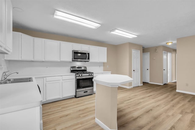 5514 Clarkston Ln, Spring, TX 77379 - kitchen featuring appliances with stainless steel finishes, a sink, light wood finished floors, and light countertops