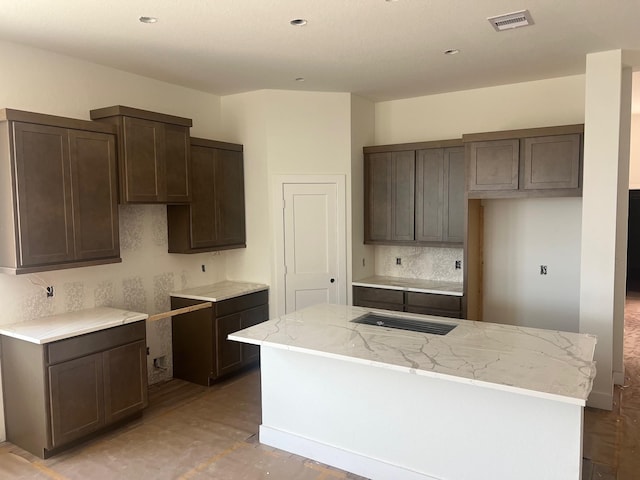 2250 Garden Arbor, Tomball, TX 77375 - kitchen featuring dark brown cabinets, a kitchen island, wood finished floors, decorative backsplash, and light stone countertops