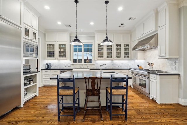 6225 Piping Rock Ln, Houston, TX 77057 - kitchen with under cabinet range hood, built in appliances, a sink, a breakfast bar, and white cabinets