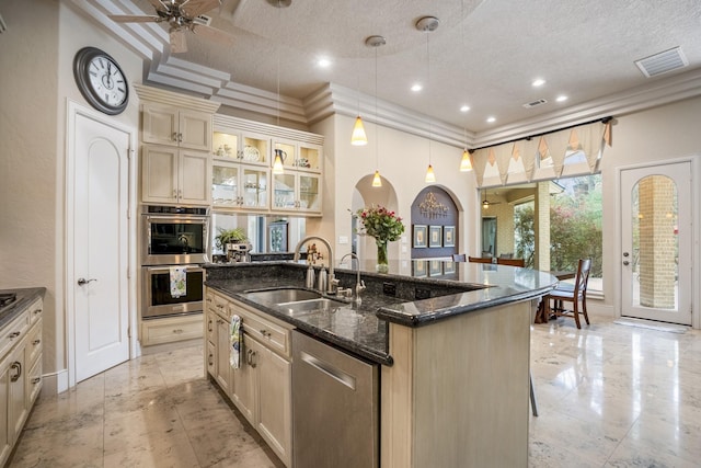 11 Bracebridge Dr, The Woodlands, TX 77382 - kitchen featuring a sink, stainless steel appliances, cream cabinets, an island with sink, and a textured ceiling