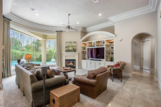 11 Bracebridge Dr, The Woodlands, TX 77382 - living area with a textured ceiling, arched walkways, ornamental molding, healthy amount of natural light, and a glass covered fireplace
