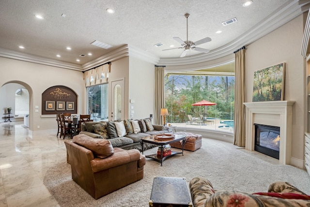11 Bracebridge Dr, The Woodlands, TX 77382 - living room featuring crown molding, a textured ceiling, arched walkways, a fireplace with flush hearth, and a ceiling fan
