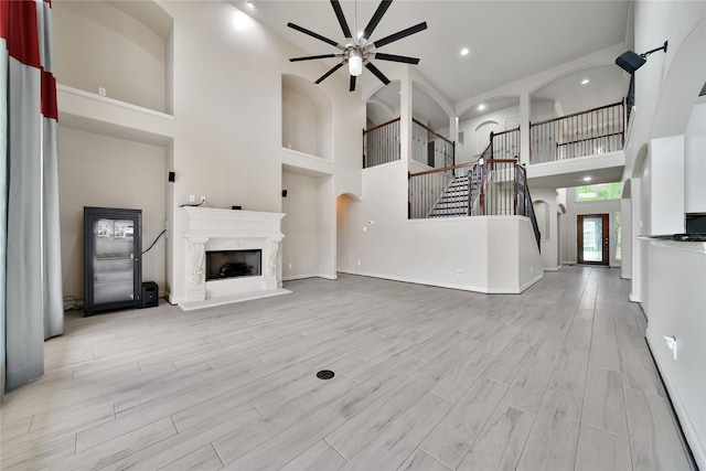 17862 Camp Cove Dr, Cypress, TX 77429 - unfurnished living room with a towering ceiling, a ceiling fan, a fireplace with raised hearth, stairs, and recessed lighting