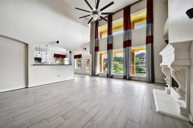 17862 Camp Cove Dr, Cypress, TX 77429 - unfurnished living room with a towering ceiling, a ceiling fan, arched walkways, plenty of natural light, and wood finished floors