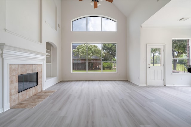 14339 Tasmania Ct, Sugar Land, TX 77498 - unfurnished living room with a ceiling fan, a tiled fireplace, plenty of natural light, wood finished floors, and a towering ceiling