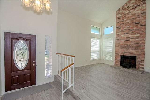 17647 Seven Pines Dr, Spring, TX 77379 - entryway with high vaulted ceiling, a chandelier, light wood-style flooring, baseboards, and a fireplace