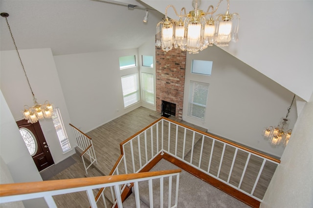 17647 Seven Pines Dr, Spring, TX 77379 - stairway with a chandelier, high vaulted ceiling, a brick fireplace, and wood finished floors