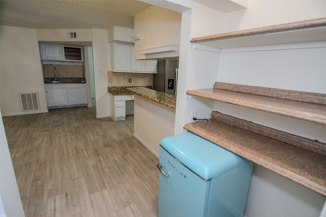 17647 Seven Pines Dr, Spring, TX 77379 - kitchen with stainless steel refrigerator with ice dispenser, decorative backsplash, refrigerator, light wood-style floors, and white cabinetry