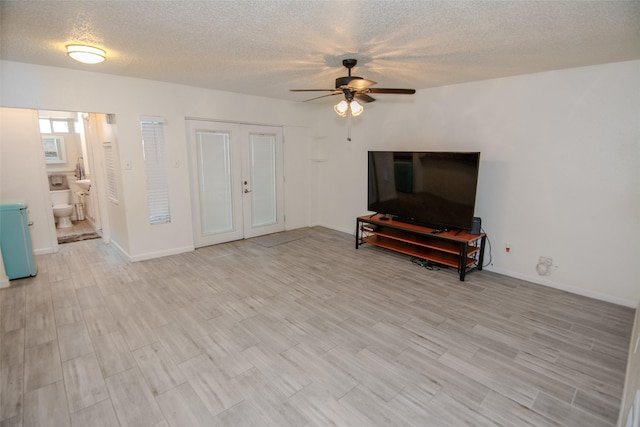 17647 Seven Pines Dr, Spring, TX 77379 - living room with ceiling fan, a textured ceiling, light wood-style floors, french doors, and baseboards