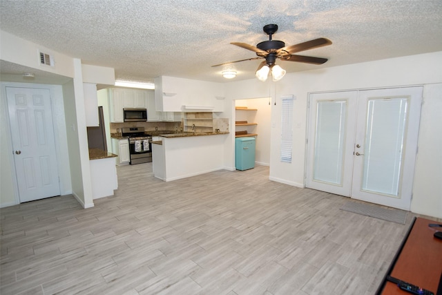 17647 Seven Pines Dr, Spring, TX 77379 - kitchen featuring appliances with stainless steel finishes, dark countertops, open floor plan, light wood finished floors, and a textured ceiling
