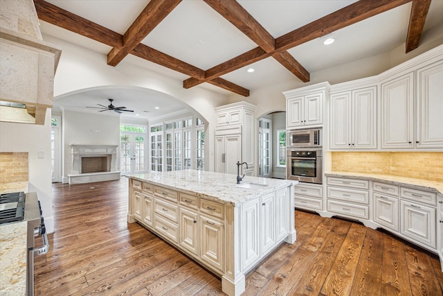 3423 Ella Lee Ln, Houston, TX 77027 - kitchen with stainless steel appliances, a sink, ceiling fan, arched walkways, and a fireplace with raised hearth