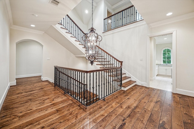 3423 Ella Lee Ln, Houston, TX 77027 - stairway featuring wood-type flooring, arched walkways, crown molding, baseboards, and a chandelier