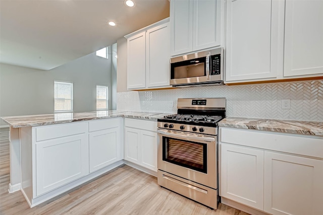 5819 Grantgrala Dr, Katy, TX 77493 - kitchen featuring stainless steel appliances, light wood finished floors, a peninsula, decorative backsplash, and white cabinetry