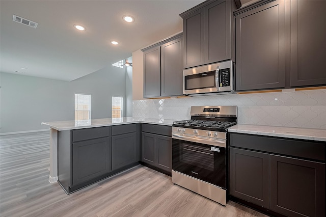 5819 Grantgrala Dr, Katy, TX 77493 - kitchen featuring appliances with stainless steel finishes, a peninsula, light wood finished floors, tasteful backsplash, and recessed lighting