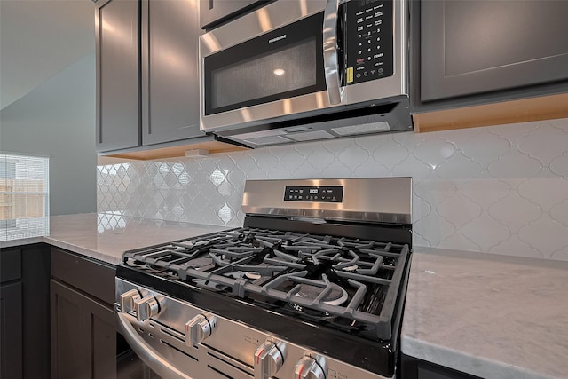 5819 Grantgrala Dr, Katy, TX 77493 - kitchen with appliances with stainless steel finishes, decorative backsplash, light stone countertops, and gray cabinetry