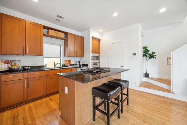 4502 Maxie St Unit A, Houston, TX 77007 - kitchen with stainless steel microwave, a sink, light wood-style flooring, a breakfast bar area, and gas cooktop