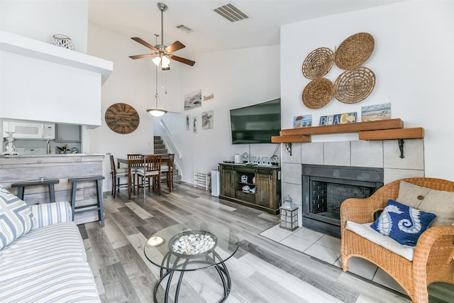 3506 Cove View Blvd Unit 506, Galveston, TX 77554 - living area featuring a ceiling fan, stairs, wood finished floors, a fireplace, and high vaulted ceiling