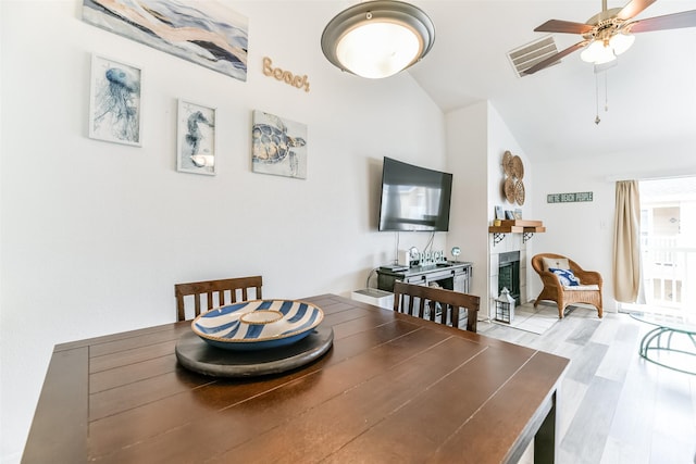3506 Cove View Blvd Unit 506, Galveston, TX 77554 - dining space with a ceiling fan, a tiled fireplace, wood finished floors, and high vaulted ceiling