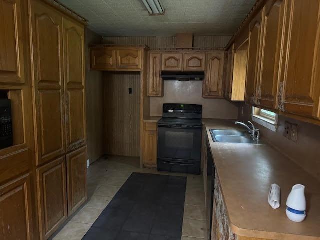 3475 Pelican St, Pinehurst, TX 77630 - kitchen featuring range, a sink, under cabinet range hood, light tile patterned floors, and brown cabinets