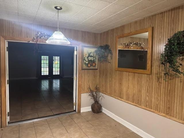3475 Pelican St, Pinehurst, TX 77630 - corridor with tile patterned flooring, wood walls, baseboards, and french doors