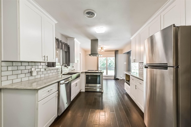 9207 Timberside Dr, Houston, TX 77025 - kitchen featuring stainless steel appliances, island exhaust hood, a sink, dark wood finished floors, and white cabinets