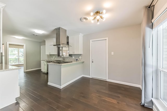 9207 Timberside Dr, Houston, TX 77025 - kitchen featuring island exhaust hood, light countertops, white cabinetry, a peninsula, and tasteful backsplash