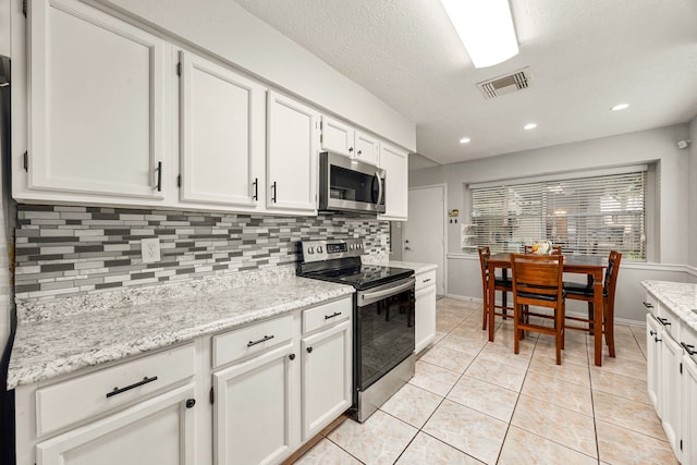 1343 Somercotes Ln, Channelview, TX 77530 - kitchen featuring appliances with stainless steel finishes, decorative backsplash, white cabinetry, light tile patterned floors, and baseboards