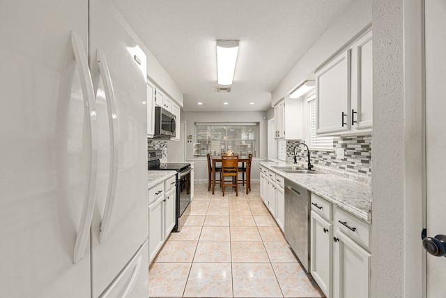 1343 Somercotes Ln, Channelview, TX 77530 - kitchen with stainless steel appliances, a sink, tasteful backsplash, and white cabinets