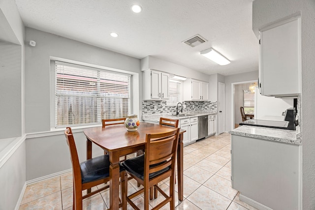 1343 Somercotes Ln, Channelview, TX 77530 - kitchen featuring white cabinets, a sink, dishwasher, light tile patterned floors, and a textured ceiling