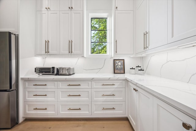 510 Wilmington Dr, Bellaire, TX 77401 - kitchen with freestanding refrigerator, white cabinets, light stone counters, and light wood-style flooring
