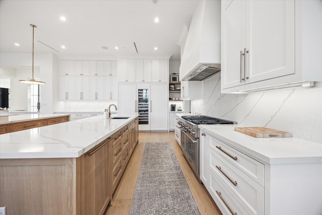 510 Wilmington Dr, Bellaire, TX 77401 - kitchen with custom range hood, stainless steel range, a sink, a large island, and light wood-type flooring