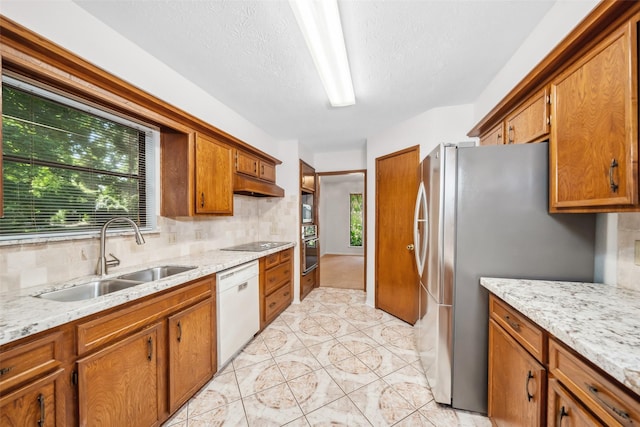 3811 Riverwood Park Dr, Houston, TX 77345 - kitchen with a sink, black appliances, brown cabinets, under cabinet range hood, and tasteful backsplash