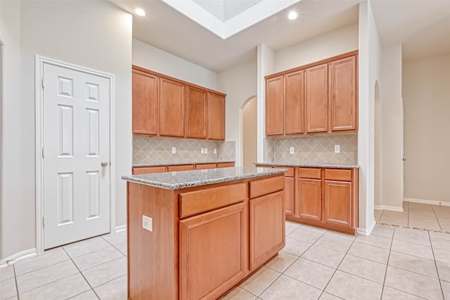 11519 Staffordale Ct, Cypress, TX 77433 - kitchen with arched walkways, light tile patterned floors, decorative backsplash, light stone counters, and recessed lighting