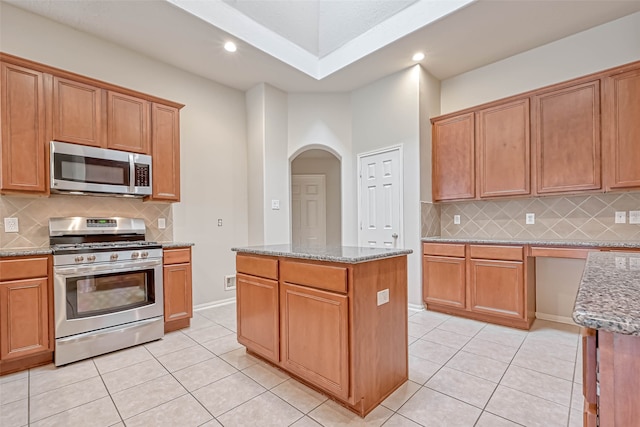 11519 Staffordale Ct, Cypress, TX 77433 - kitchen with stainless steel appliances, arched walkways, light stone counters, light tile patterned floors, and recessed lighting