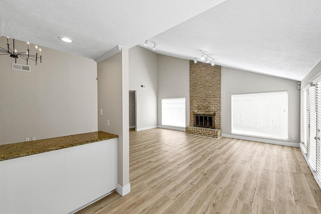 12014 Briar Forest Dr, Houston, TX 77077 - unfurnished living room with lofted ceiling, rail lighting, a textured ceiling, light wood-type flooring, and a chandelier