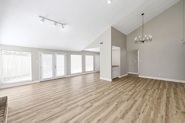 12014 Briar Forest Dr, Houston, TX 77077 - unfurnished living room with track lighting, a chandelier, high vaulted ceiling, light wood finished floors, and baseboards